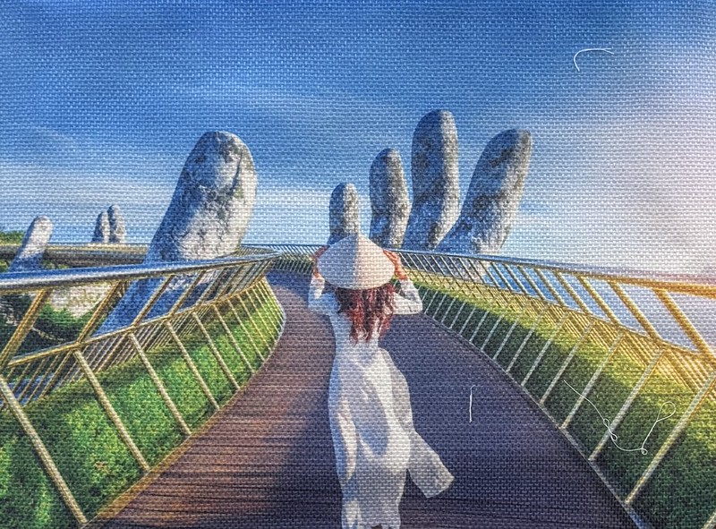 The Golden hand bridge shown on a woven bag, the bridge is held up with 2 giant stone hands and has a golden platform. In this picture there is a single woman with her back to us wearing a conical hat