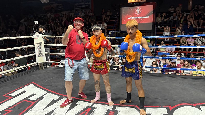 Me in a boxing ring posing with two Muay Thai boxers one in red shorts the other in blue