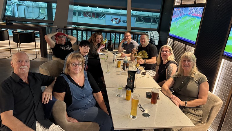 A group of friends sat a round a table in a bar, drinking alcohol