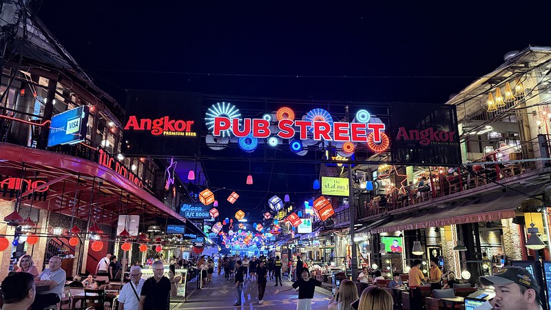 An asian street with many lanterns and hundreds of lights in in big illuminated letters above the street reads Pub Street