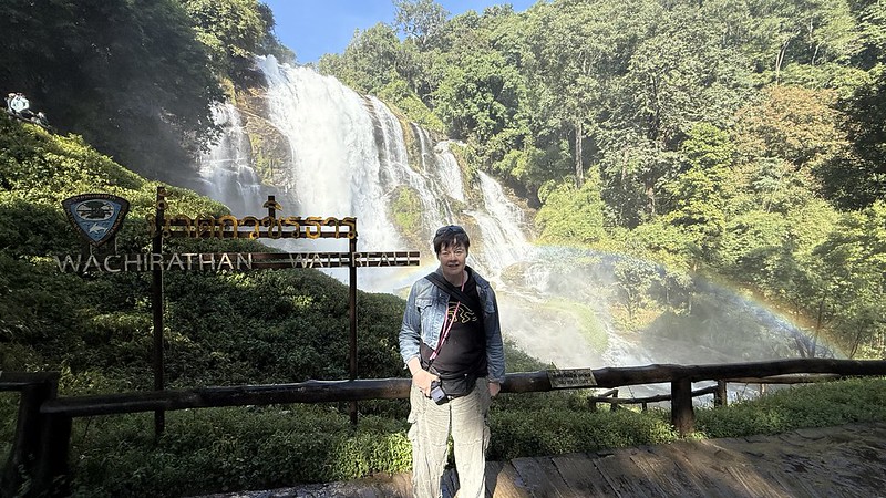 Susan stood in front of the Wachirathan Waterfall there is a rainbow from all of the spray